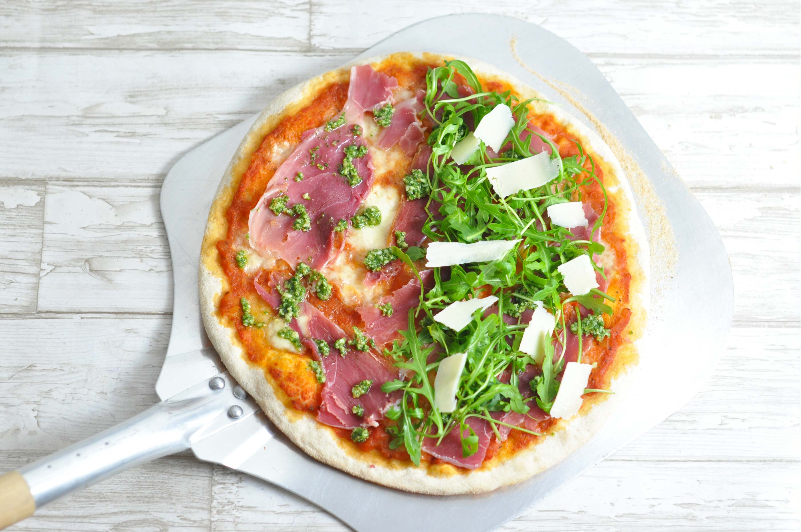 Pizza with parma ham, pesto, rocket and parmesan