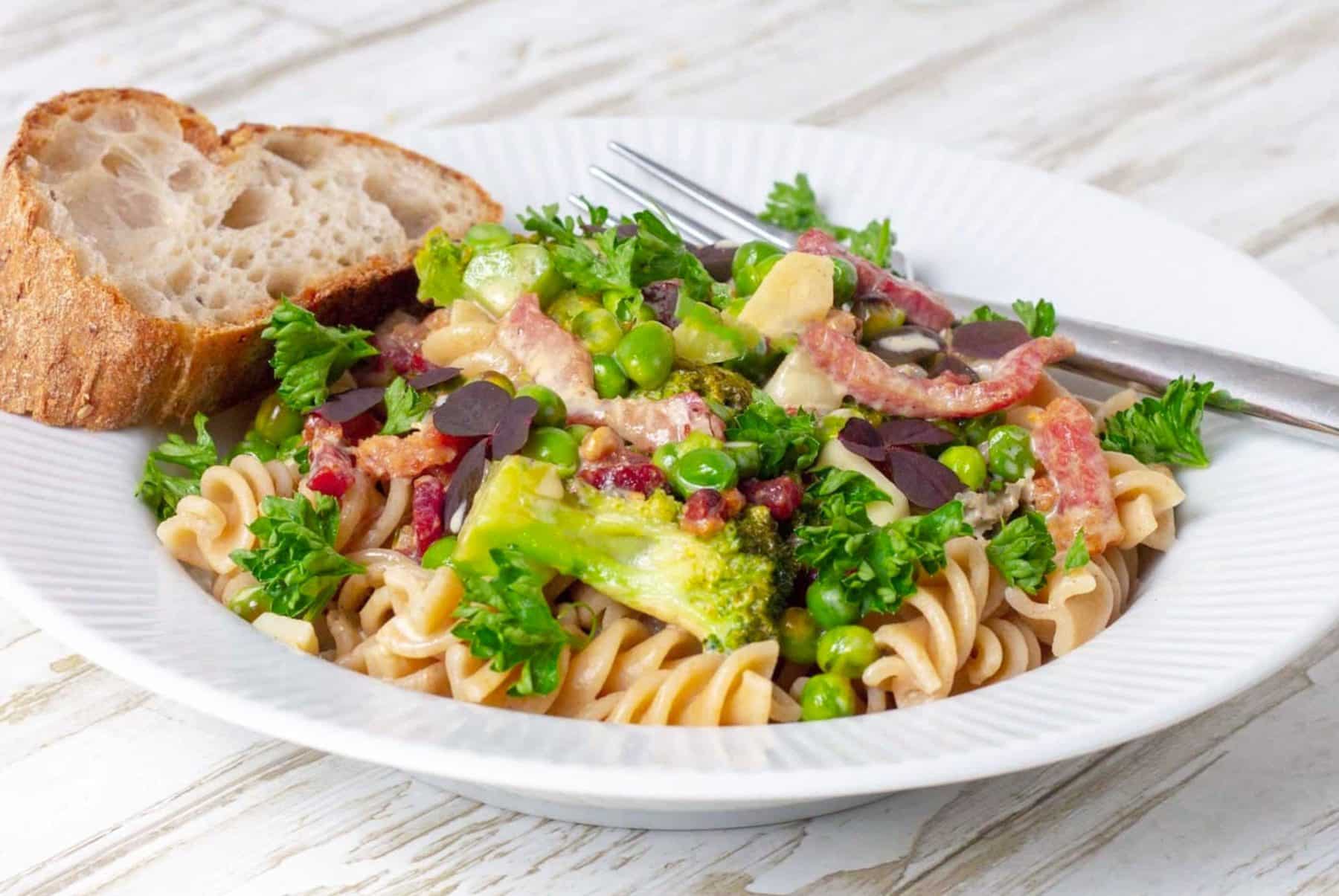 Easy pasta with bacon, broccoli and peas in creamy sauce