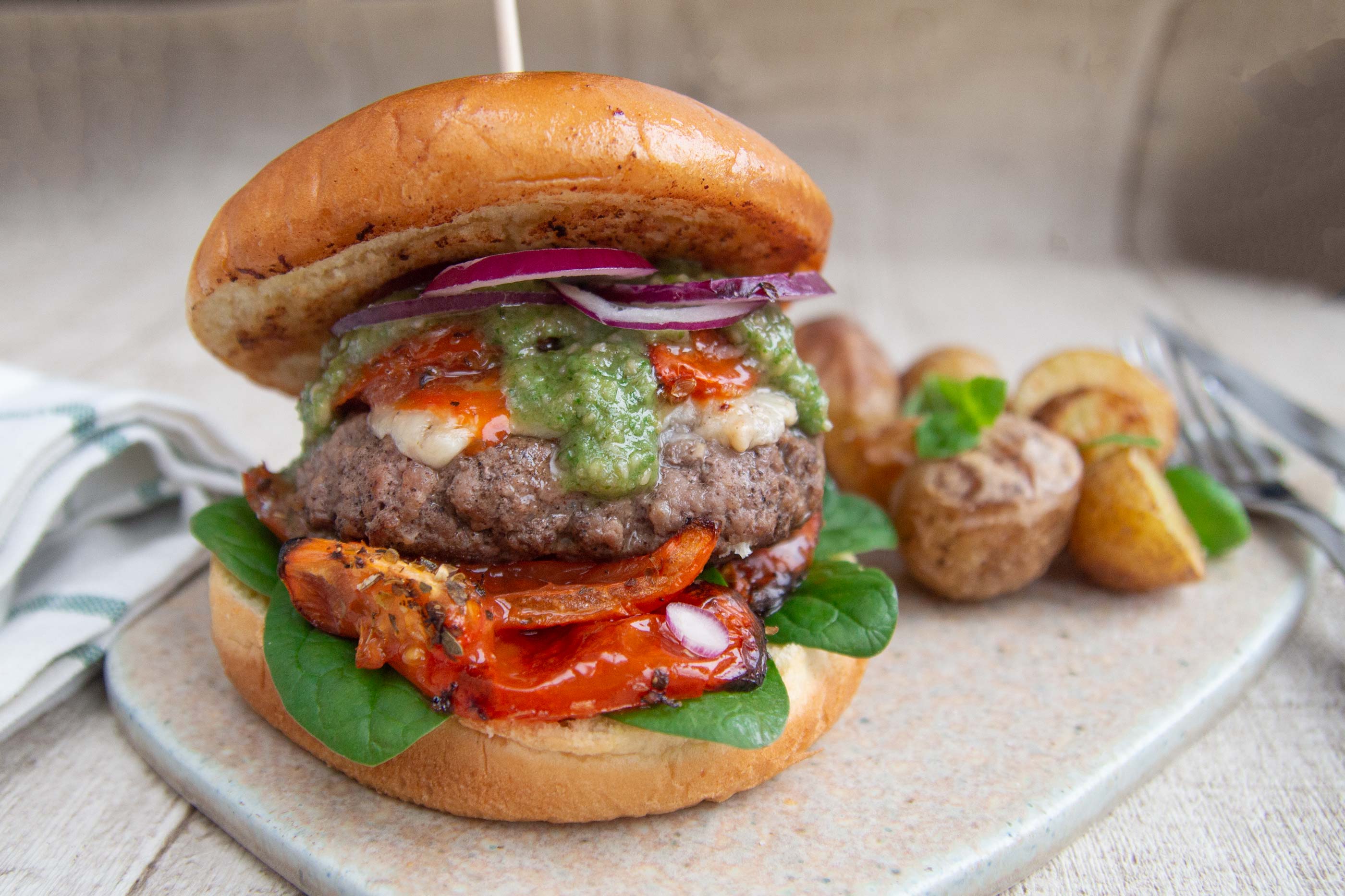 Italian burgers with baked tomatoes, potatoes and pesto